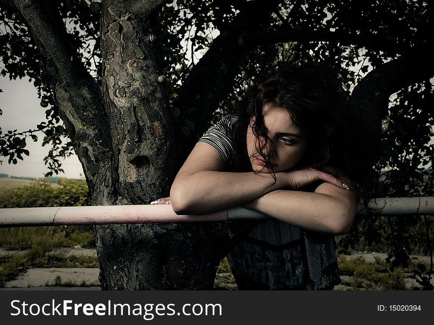 Young redhead woman at fence under apple tree. Young redhead woman at fence under apple tree