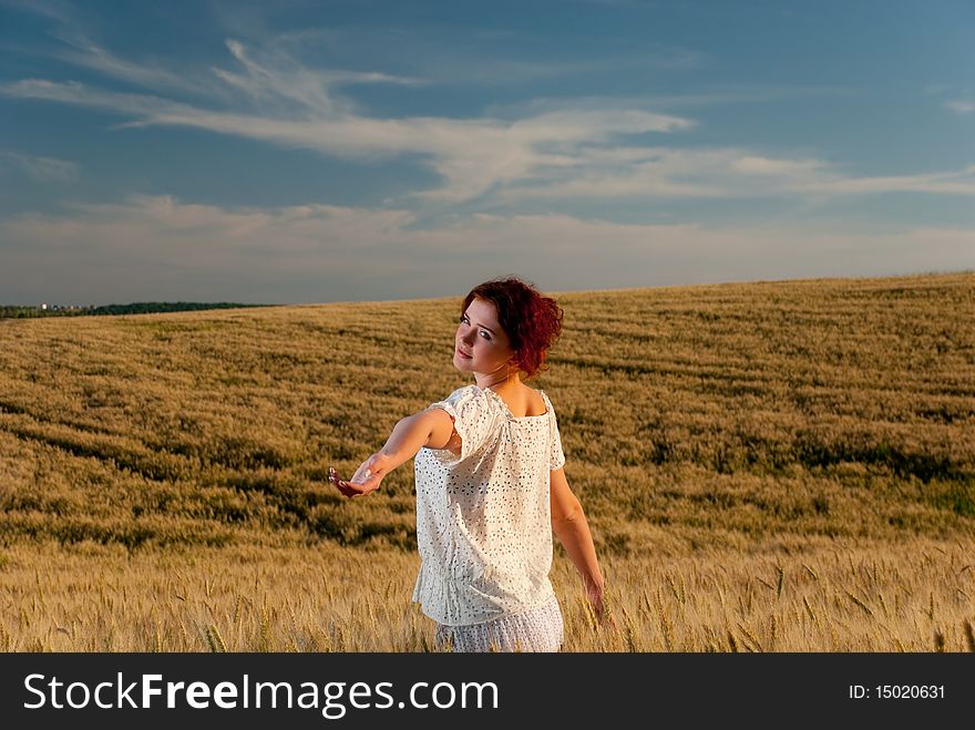 Young redhead woman reaching out at wheat field. Young redhead woman reaching out at wheat field