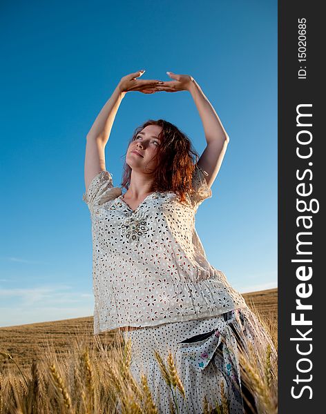 Young redhead woman relaxing at wheat field. Young redhead woman relaxing at wheat field