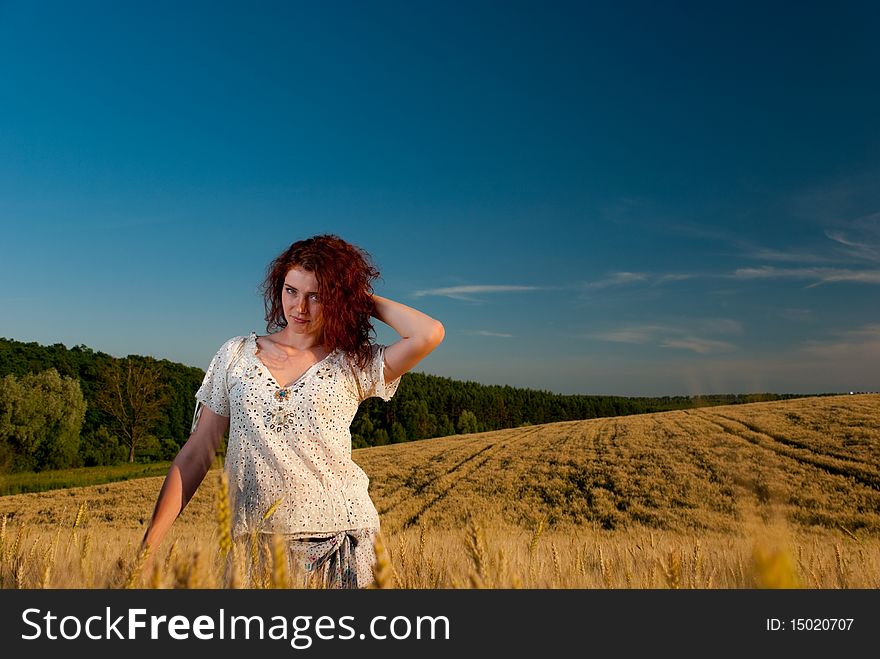 Young redhead woman relaxing at wheat field. Young redhead woman relaxing at wheat field