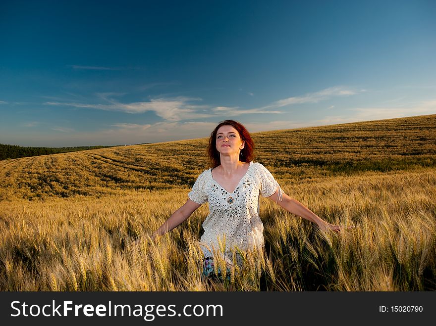 Young redhead woman at wheat field sunset. Young redhead woman at wheat field sunset