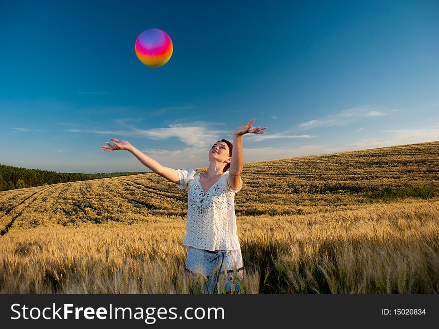 Young redhead woman at wheat field playing a ball. Young redhead woman at wheat field playing a ball