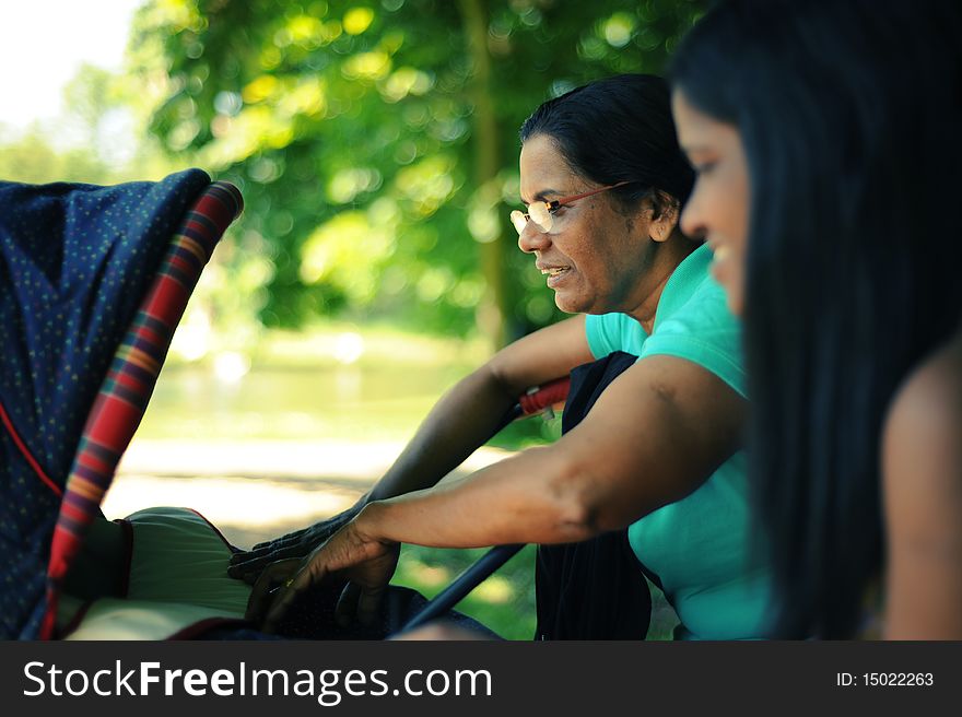 A mother and a grandmother looking at a baby in a carriage. A mother and a grandmother looking at a baby in a carriage