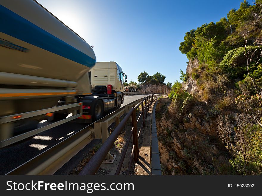 The modern truck driving fast on mountain bridge on a sunny day