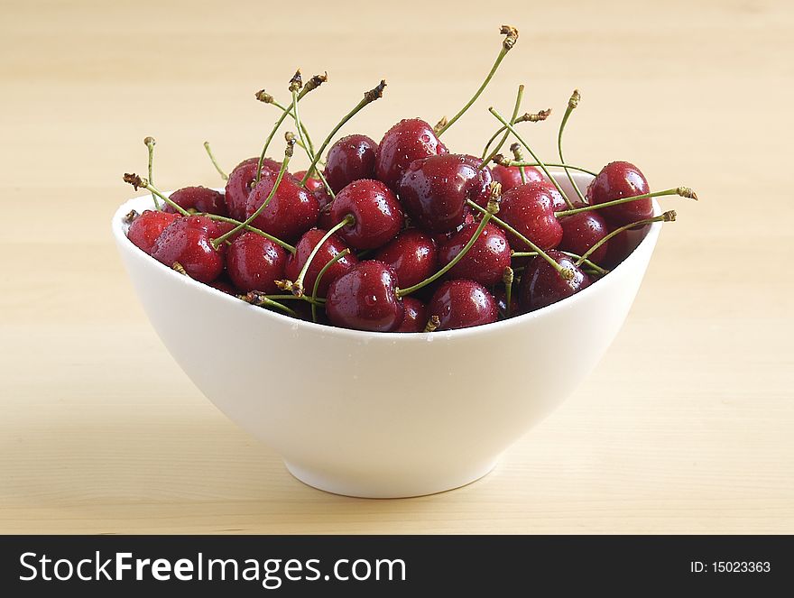 Bowl of fresh ripe cherries on light background