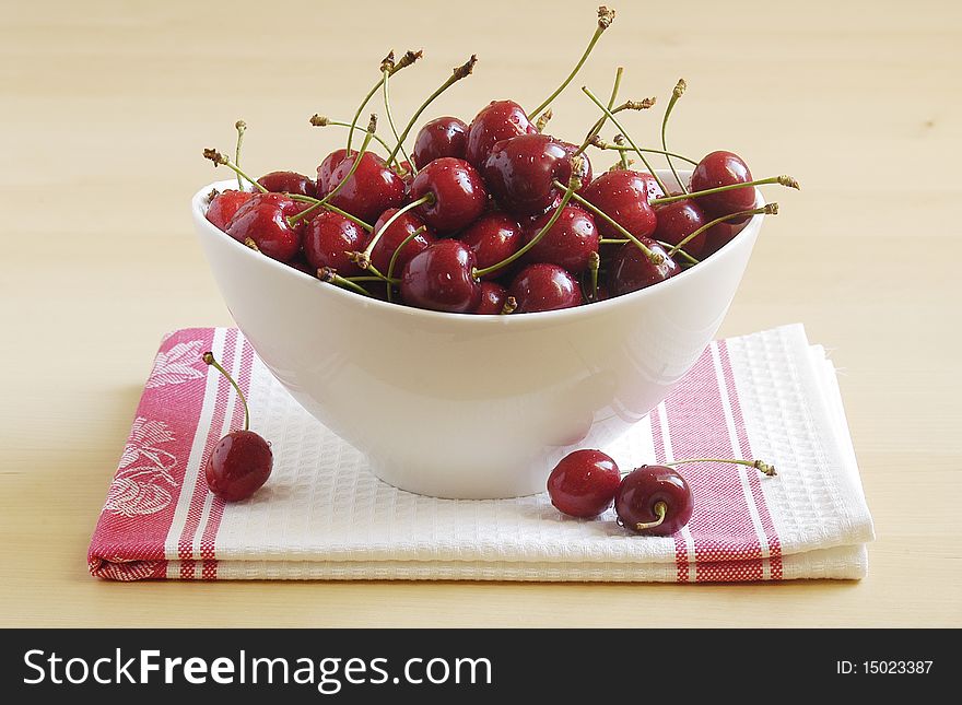 Bowl of fresh ripe cherries on light background