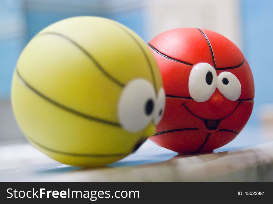 Two small balls with funny faces supported by a marble. Two small balls with funny faces supported by a marble