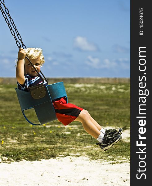 Toddler on a swing at the playground. Toddler on a swing at the playground