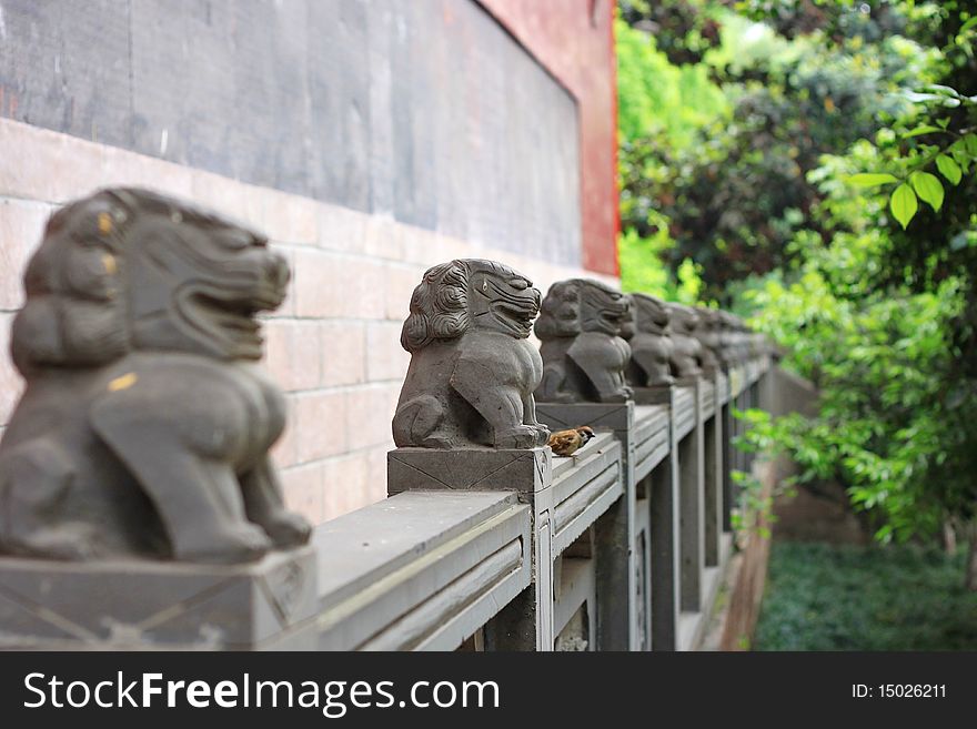 A bird stands with the stone lions. In the Buddhism temple in China.