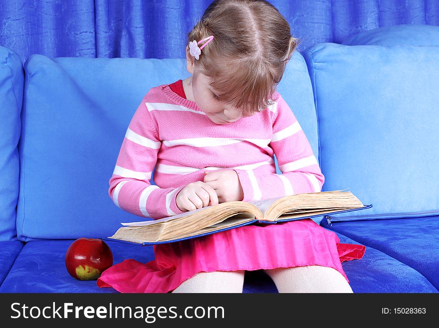 Girl reading book with apple at sofa
