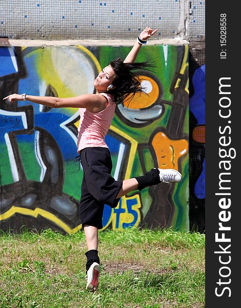 Woman modern ballet dancer in sity against graffiti wall