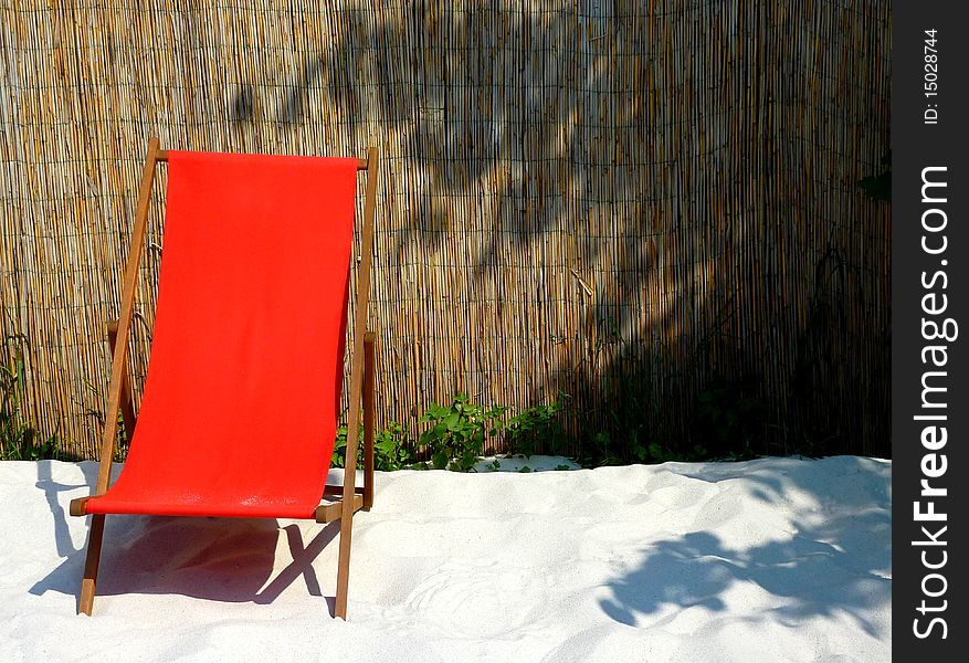 Red sun-lounger on a white sand