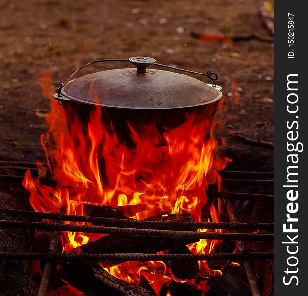 Food in the cauldron is prepared on the wood open fire in the summer in nature in the marching version. Food in the cauldron is prepared on the wood open fire in the summer in nature in the marching version