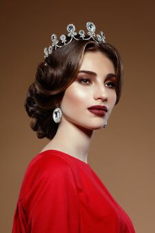Closeup Portrait Of Young Woman, Diamond Crown And Earring. Brunette Gorgeous Woman,  On A Beige Background. Stock Photos