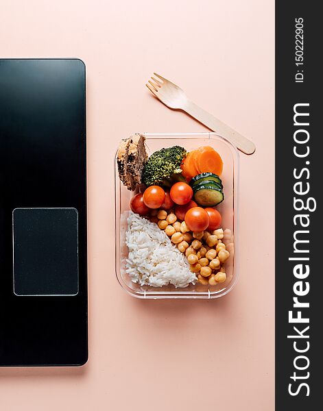 Healthy food in lunch box, on working table with laptop