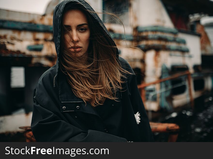 Young woman posing against the background of an old abandoned ship