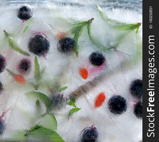Background    green leaves of mint, berry of blueberry  Wolfberry, Goji berry,    in ice   cube with air bubbles. Background    green leaves of mint, berry of blueberry  Wolfberry, Goji berry,    in ice   cube with air bubbles