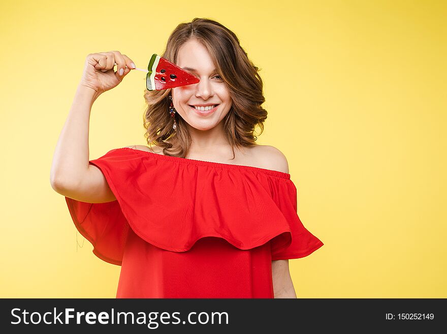 Close up portrait of attractive lovely girl in light dress handing lolipop isolated on yellow background. Close up portrait of attractive lovely girl in light dress handing lolipop isolated on yellow background