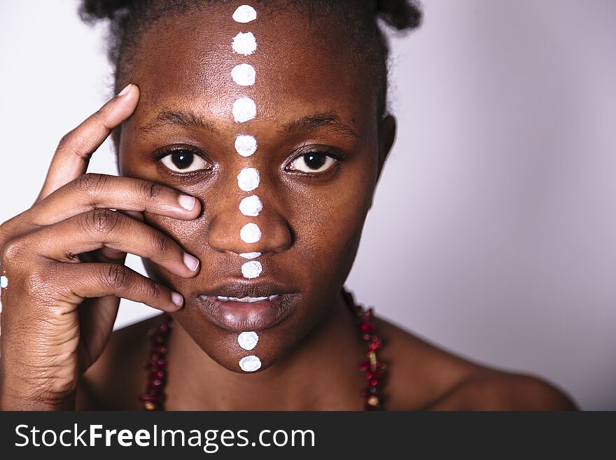 Painted face of young african girl with pattern from white dots close up