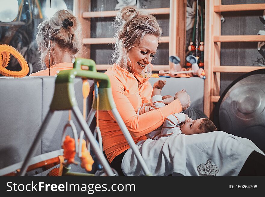 Cheerful happy mom is plaing with her pretty baby at pediatrician cabinet full of special treatment equipment. Cheerful happy mom is plaing with her pretty baby at pediatrician cabinet full of special treatment equipment.