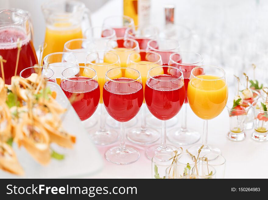 Table top full of glasses Glasses not alcoholic drinks, orange juice, water and berry juice. s with canapes and