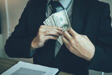 Businessman Putting Stack Of Money Bills In His Suit Coat Pocket Stock Photos
