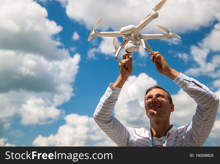 A handsome man holding a drone on the background of cloudy sky, copy space. lifestyle, recreation concept.