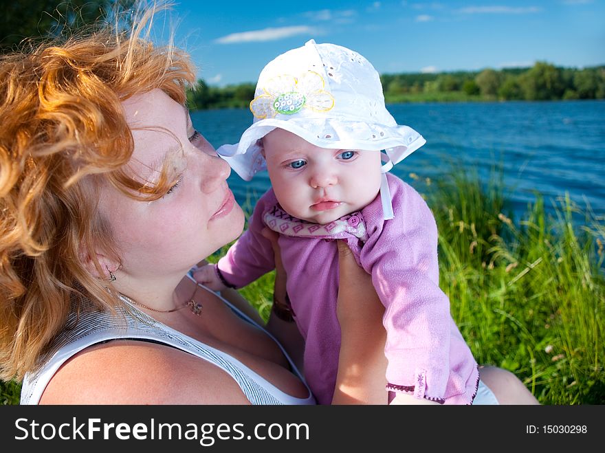 Baby in mothers arms at summer season riverside. Baby in mothers arms at summer season riverside