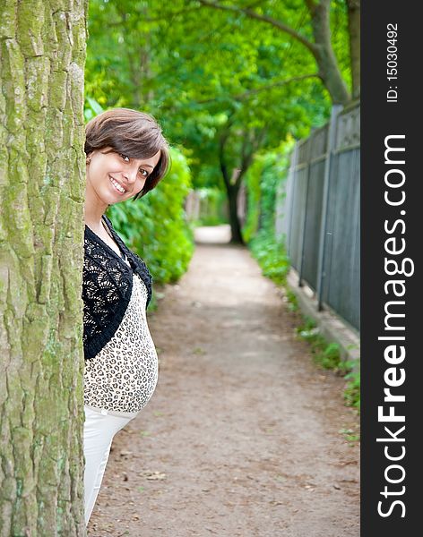Beautiful pregnant woman in the park near tree. Beautiful pregnant woman in the park near tree