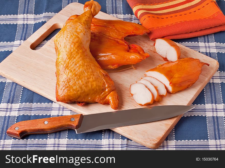 Meat smoked chicken on a wooden cutting board.