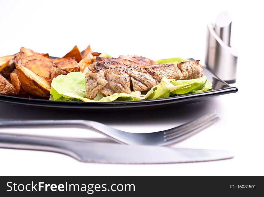 Pork and fried potatos on black plate. Pork and fried potatos on black plate