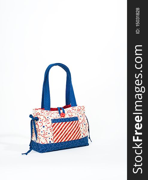 A quilted tote bag in patriotic colors shot on a white backdrop. A quilted tote bag in patriotic colors shot on a white backdrop
