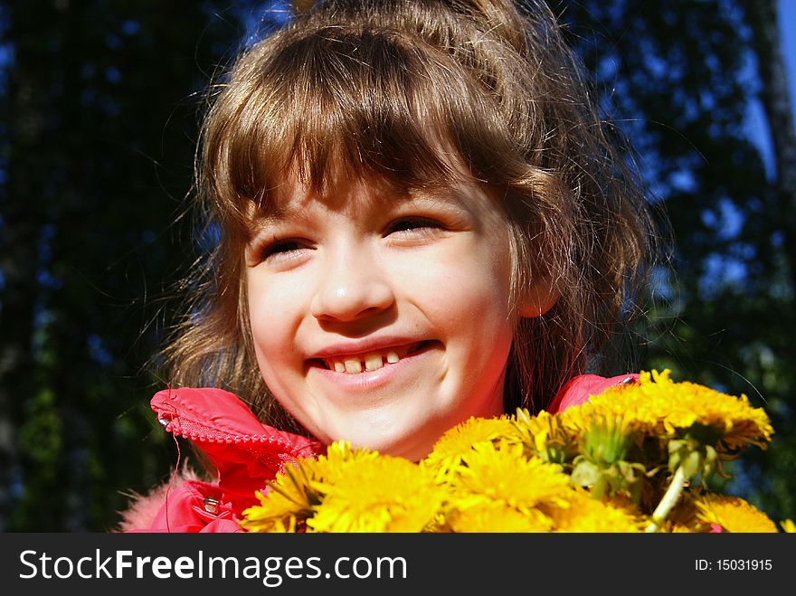 The joyful child on the nature with a bouquet of yellow flowers. The joyful child on the nature with a bouquet of yellow flowers