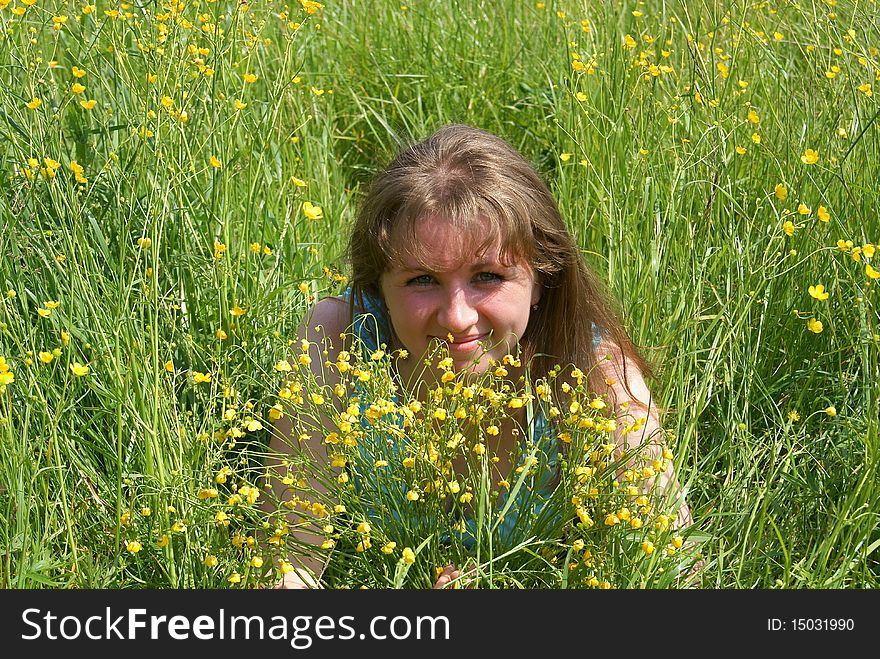 The happy woman lays on a green grass in the summer in park with yellow flowers. The happy woman lays on a green grass in the summer in park with yellow flowers