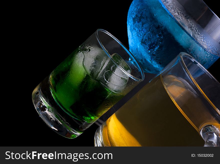 Three colored cocktail with ice in glasses on a black background