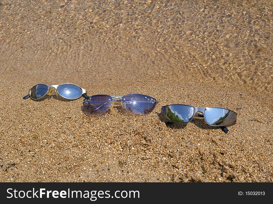 In the summer on sand at water man's, female and children's sun glasses lay