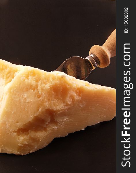 Still life of parmesan cheese with a knife on a black background