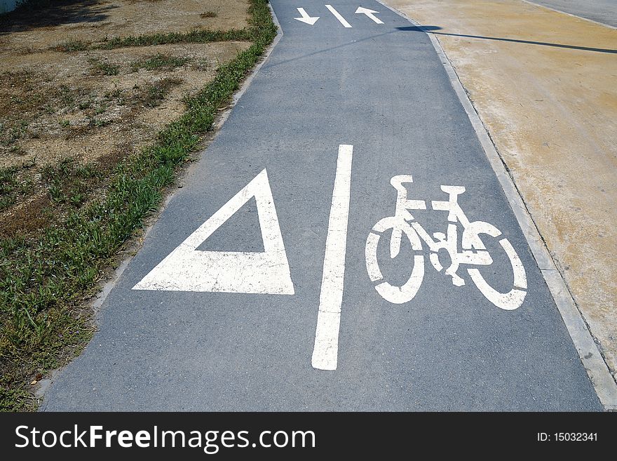 White symbols over dry asphalt bicycle road in bright summer day