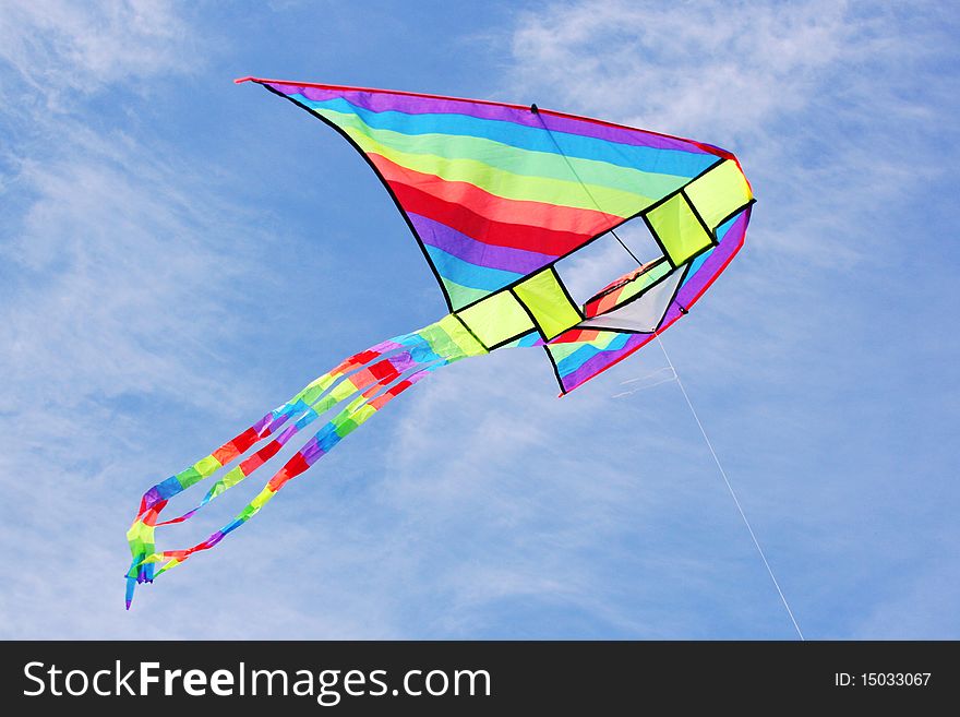 Bright multicolored kite in blue cloudy sky. Bright multicolored kite in blue cloudy sky