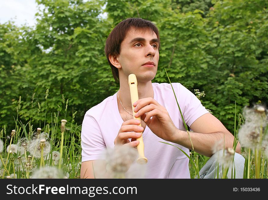 Young Man Playing On Flute At Summer Time