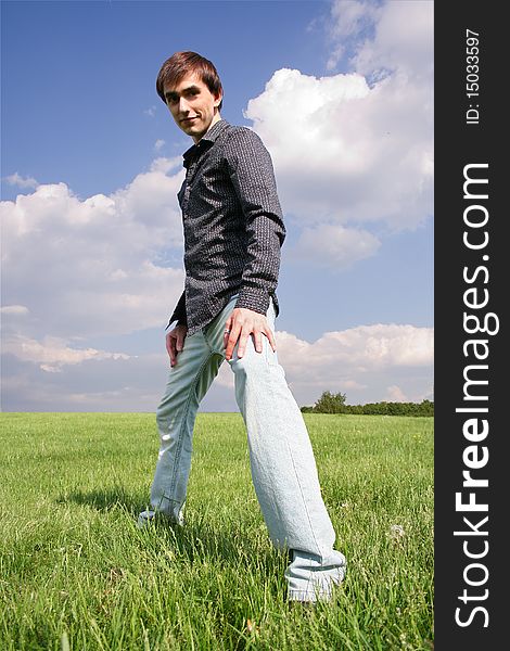 Young man in black shirt standing on green lawn at summer time