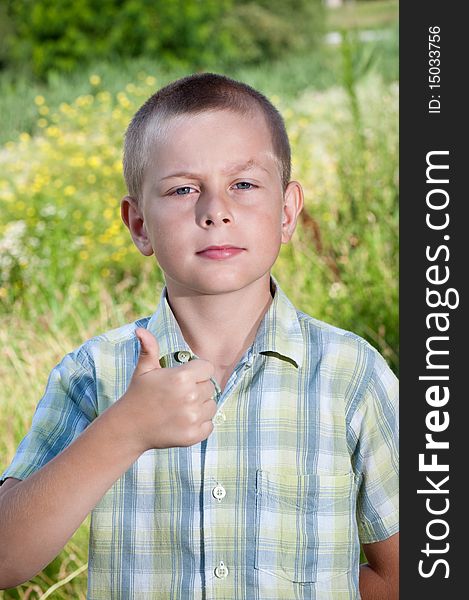 Thumb up from young boy in nature on a sunny day