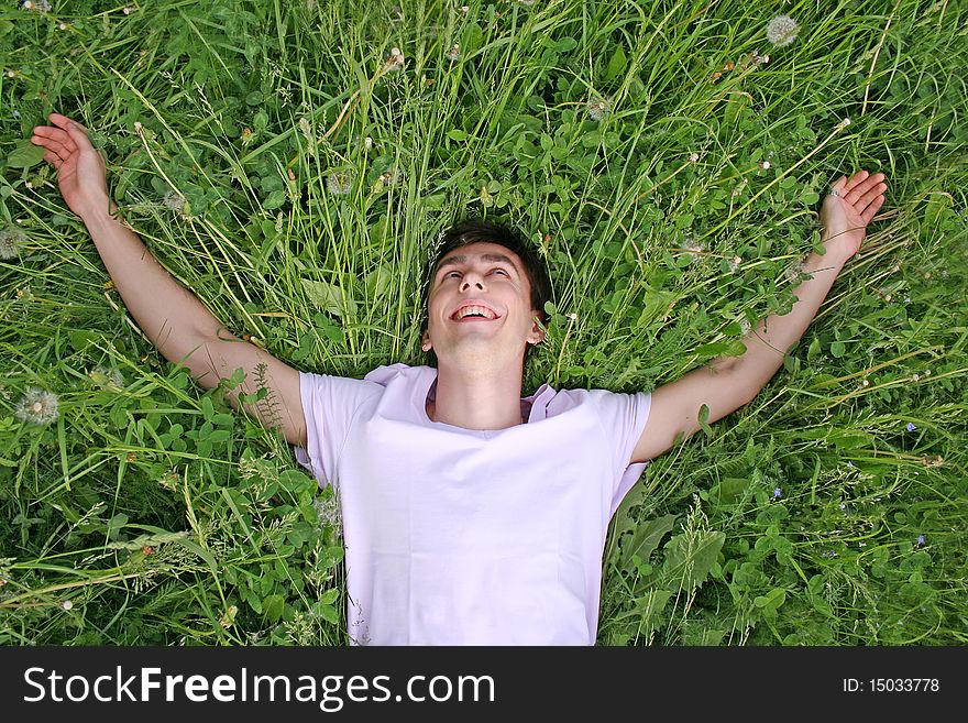 Young man lies on grass and laughing view from above