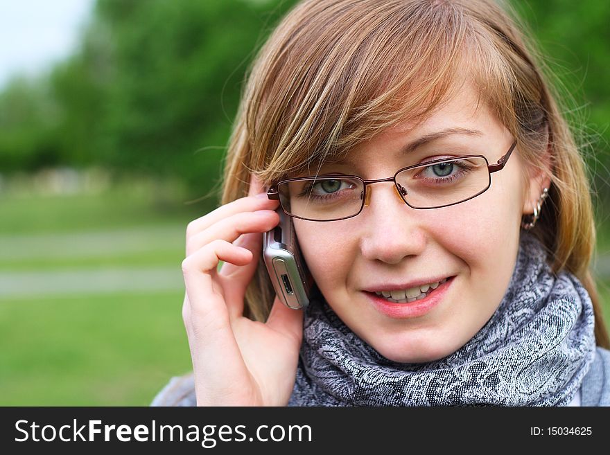 The young girl speaks by phone, in park. The young girl speaks by phone, in park