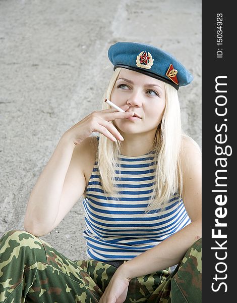 The woman in the military form sits and smokes. The woman in the military form sits and smokes