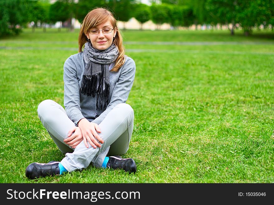 The girl sits on a grass