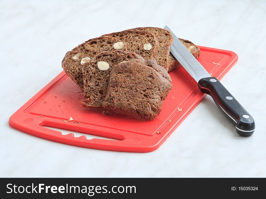 Sliced brown bread on a red board with a knife