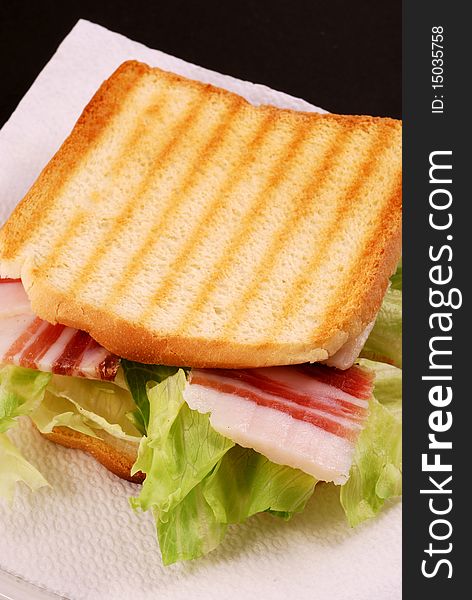 Toast with bacon, cheese and salad on a black background. Toast with bacon, cheese and salad on a black background