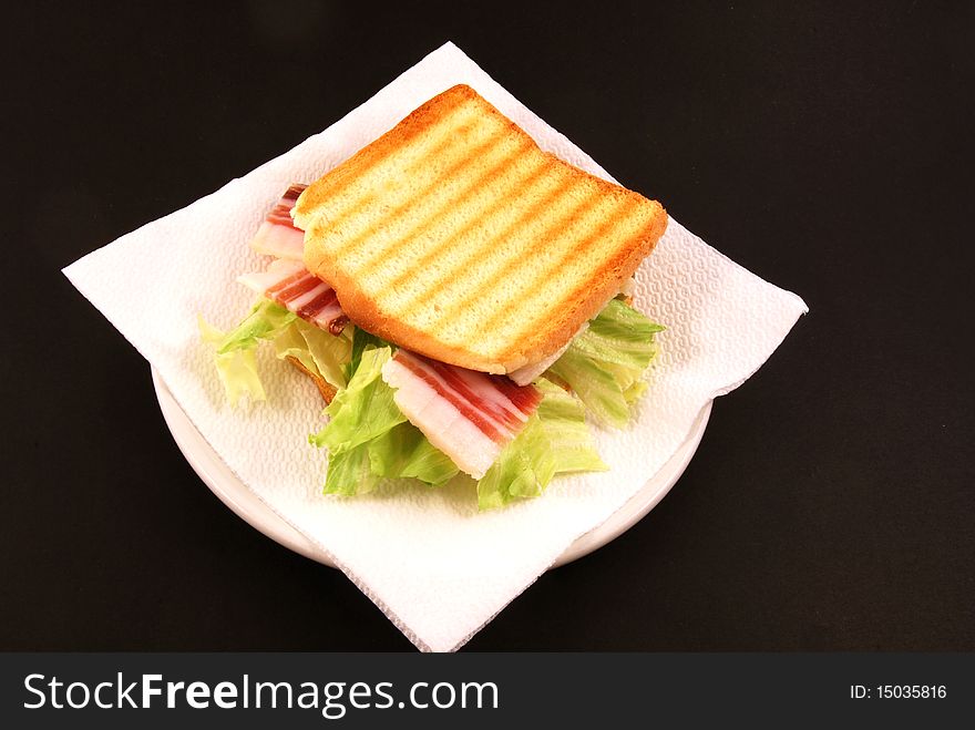 Toast with cheese, bacon and salad on a black background. Toast with cheese, bacon and salad on a black background