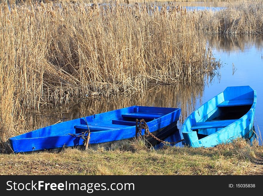 Two moored boats with a rushy lake on the background. Two moored boats with a rushy lake on the background